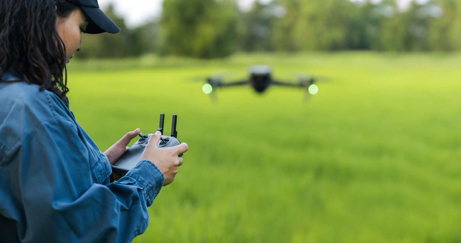 Operátor s ovladačem a dron nad polem